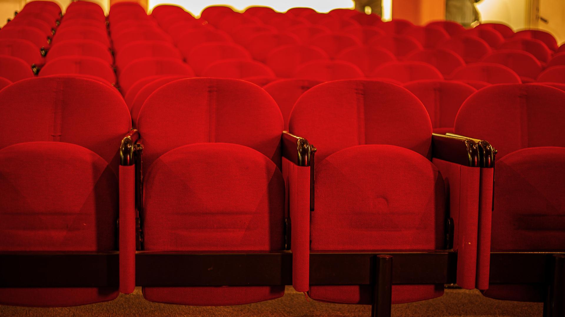 Mehrere leere Reihen Kinosessel in einem Kino.