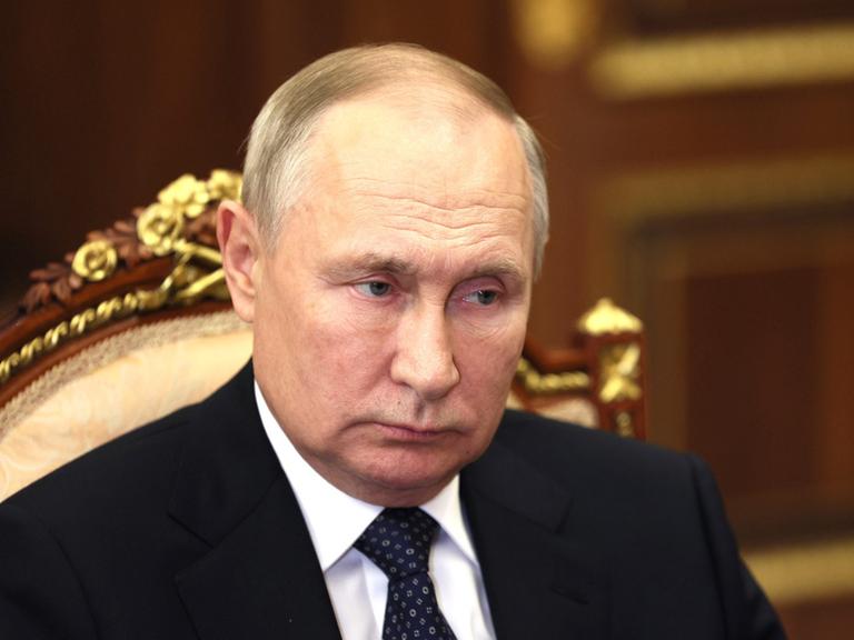 Der russische Präsident Wladimir Putin sitzt auf einem verzierten Stuhl mit Goldrand und blickt nachdenklich zur Seite.
