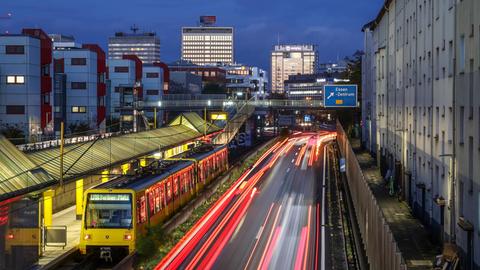 Autobahn A40 in der Essener Innenstadt während der Abenddämmerung. Rechts stehen Wohnhäuser hinter einer Schallschutzwand. 
