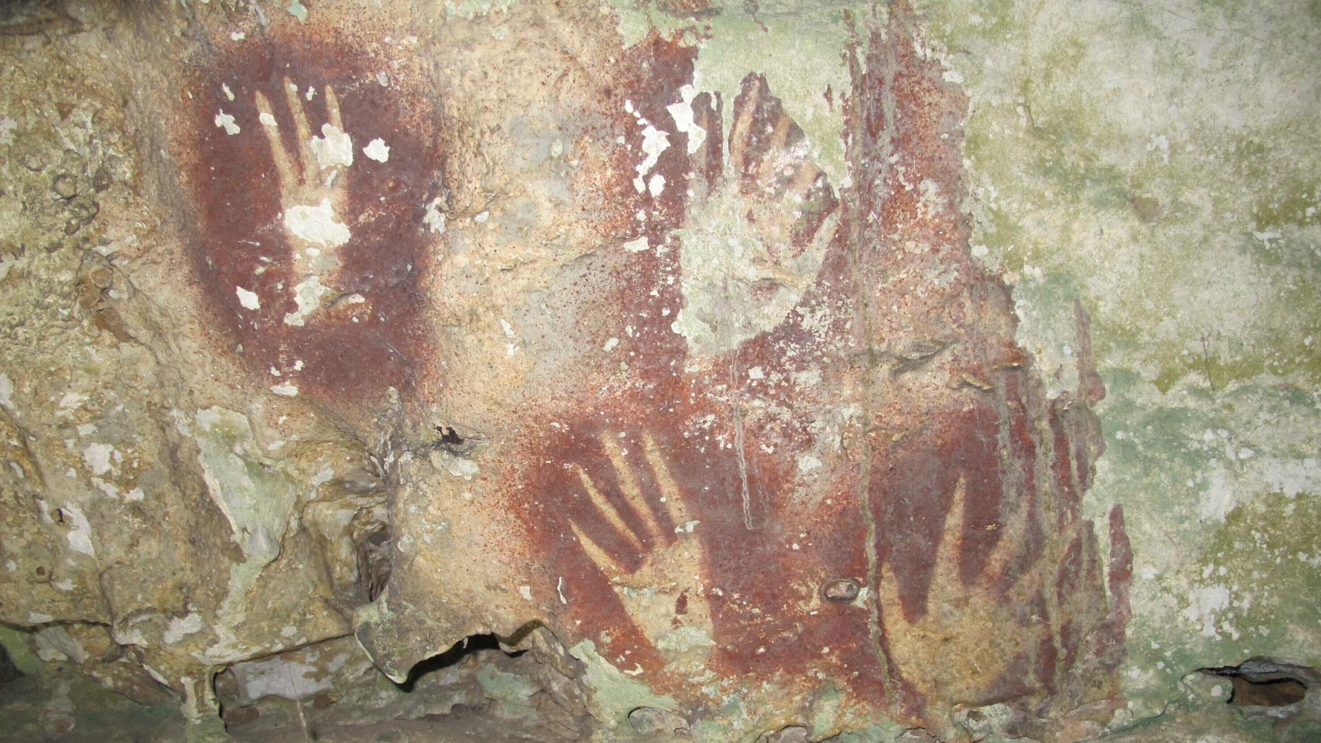 Das Bild des Forschers Maxime Aubert zeigt Hände mit spitz zulaufenden Fingern - die Hand diente als Schablone, Farbpigmente wurden auf die Höhlenwand in der Region Maros, Sulawesi, geblasen. Das Bild des Forschers Maxime Aubert zeigt Hände mit spitz zulaufenden Fingern - die Hand diente als Schablone, Farbpigmente wurden auf die Höhlenwand in der Region Maros, Sulawesi, geblasen.