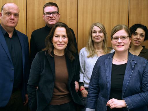 Die Podcasterinnen Robin Alexander, Ulf Buermeyer, Anne Will, Tina Hildebrandt, Nadine Lindner und Katharina Hamberger (v.l.n.r.) stehen vor einer Studiowand.