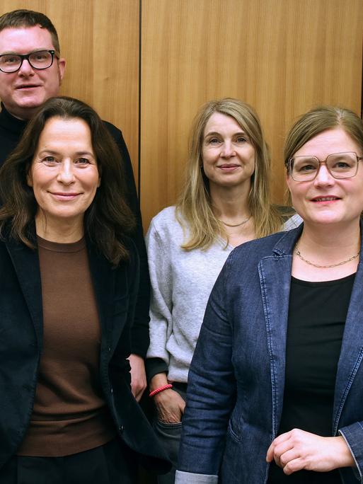 Die Podcasterinnen Robin Alexander, Ulf Buermeyer, Anne Will, Tina Hildebrandt, Nadine Lindner und Katharina Hamberger (v.l.n.r.) stehen vor einer Studiowand.