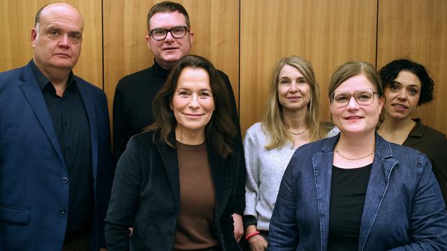 Die Podcasterinnen Robin Alexander, Ulf Buermeyer, Anne Will, Tina Hildebrandt, Nadine Lindner und Katharina Hamberger (v.l.n.r.) stehen vor einer Studiowand.
