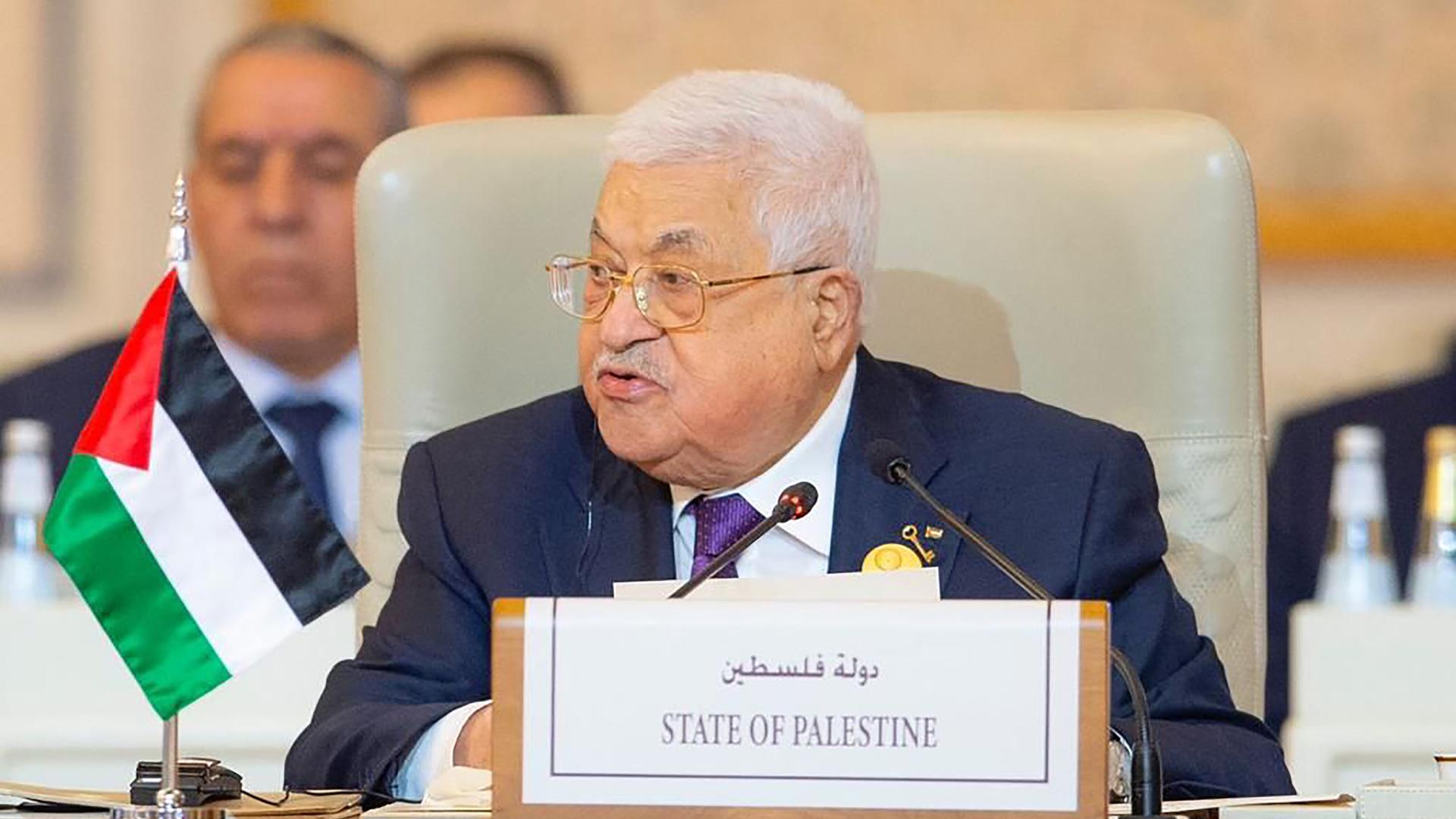 Mahmoud Abbas bei einem Notfallmeeting der Arabischen Liga. Er sitzt an einem Konferenztisch, auf dem Schild vor ihm steht auf Englisch und Arabisch "State of Palestine". Er schaut leicht zur Seite.