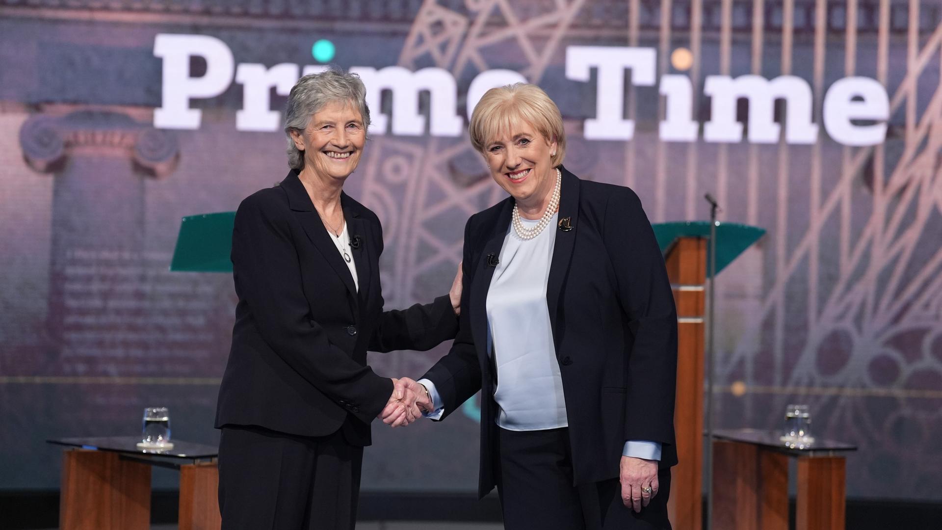 Bei der Präsidentenwahl in Irland kandidieren Heather Humphrey (rechts) und Catherine Connolly. Sie schütteln sich in einem Fernsehstudio die Hände. Hinter ihnen steht ein Schriftzug "Prime Time".   Bei der Präsidentenwahl in Irland kandidieren Heather Humphrey (rechts) und Catherine Connolly. Sie schütteln sich in einem Fernsehstudio die Hände. Hinter ihnen steht ein Schriftzug "Prime Time".