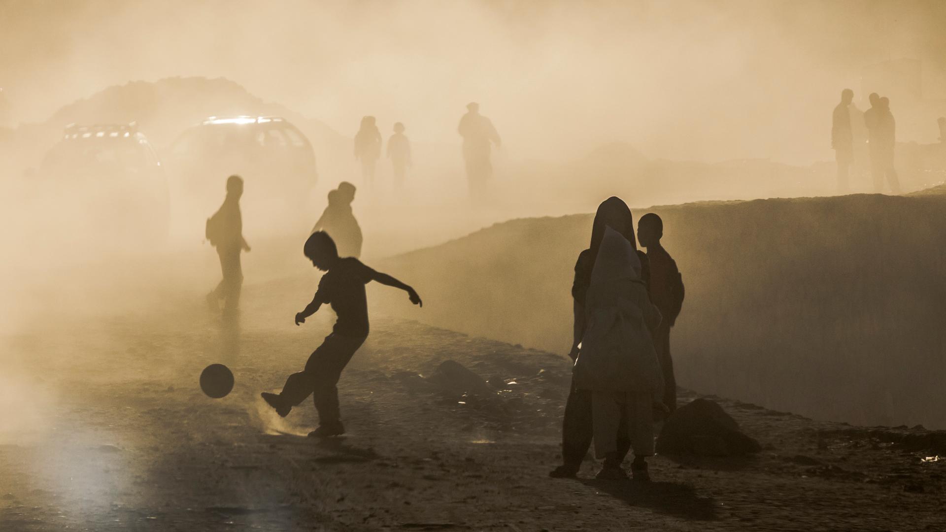 Ein Junge spielt Fußball auf einer Straße in Kabul (Afghanistan). Ein Junge spielt Fußball auf einer Straße in Kabul (Afghanistan).