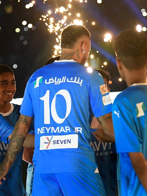 Brasiliens Superstar Neymar Jr. im Trikot seines neuen Vereins Saudi Al Hilal wird von mehreren Jungen abgeklatscht, als er das Stadion betritt, es ist dunkel.