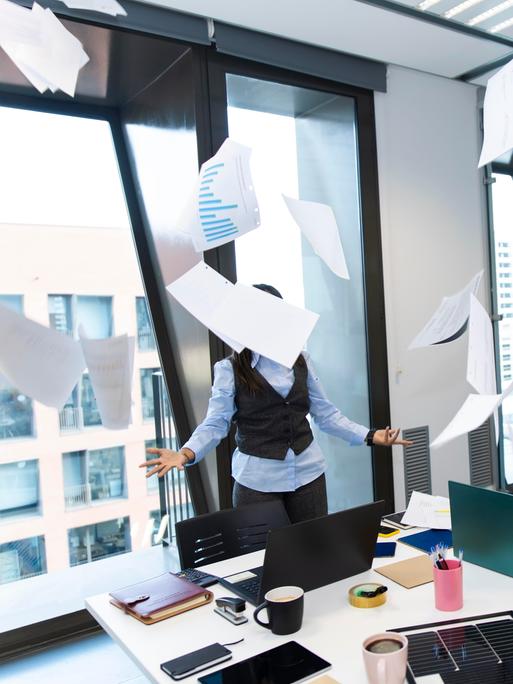 Gestresster Manager, der mit Papier um sich wirft in einem modernen Büro. 