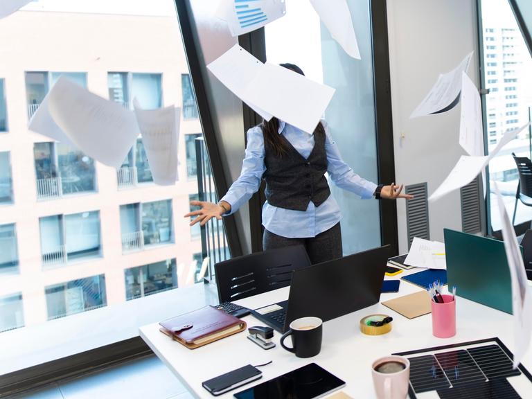 Gestresster Manager, der mit Papier um sich wirft in einem modernen Büro. 