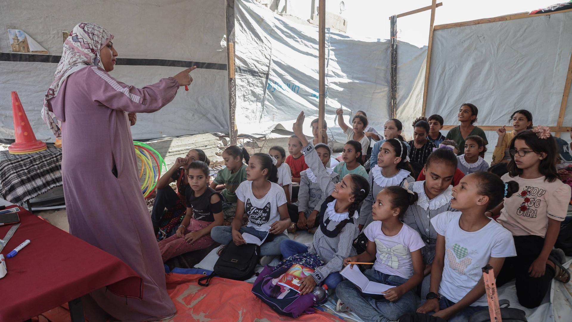 Das Foto zeigt eine Lehrerin in einem Zelt im Gaza-Streifen, die Kinder unterrichtet.