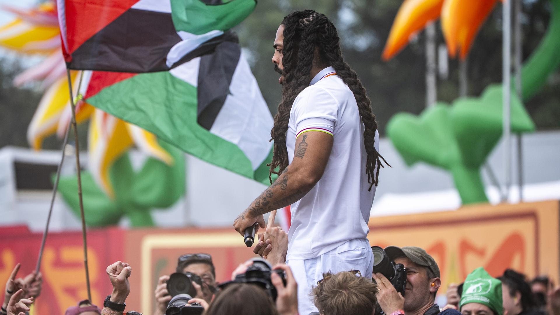 Der Musiker Bob Vylan auf der Bühne des Glastonbury Festivals. Im Hintergrund sind palästinensische Flaggen zu sehen. Der Musiker Bob Vylan auf der Bühne des Glastonbury Festivals. Im Hintergrund sind palästinensische Flaggen zu sehen.