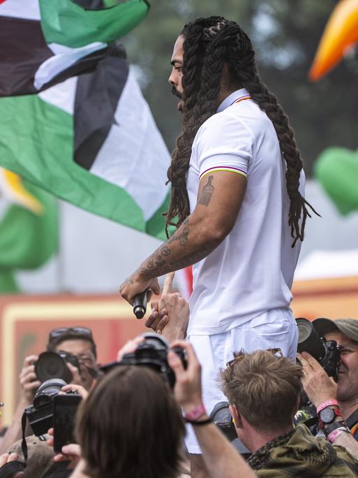 Der Musiker Bob Vylan auf der Bühne des Glastonbury Festivals. Im Hintergrund sind palästinensische Flaggen zu sehen. 