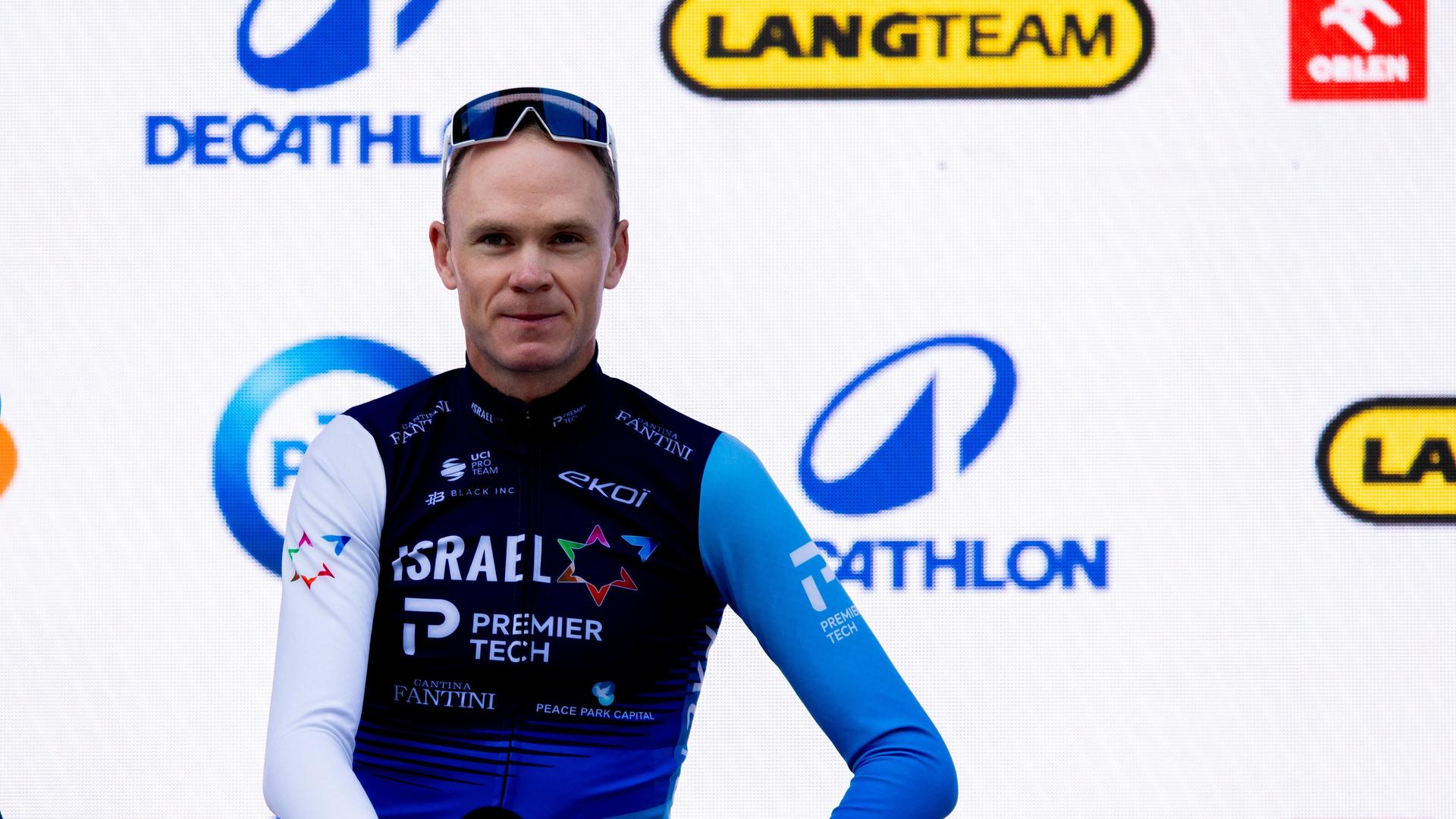 Chris Froome sitzt auf einer Bühne auf seinem Rad und hält ein Mikrofon in der Hand. Chris Froome sitzt auf einer Bühne auf seinem Rad und hält ein Mikrofon in der Hand.