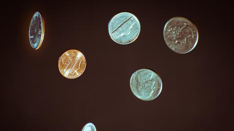 Vereinzelt schwebende oder fallende Münzen vor einem schwarzen Hintergrund