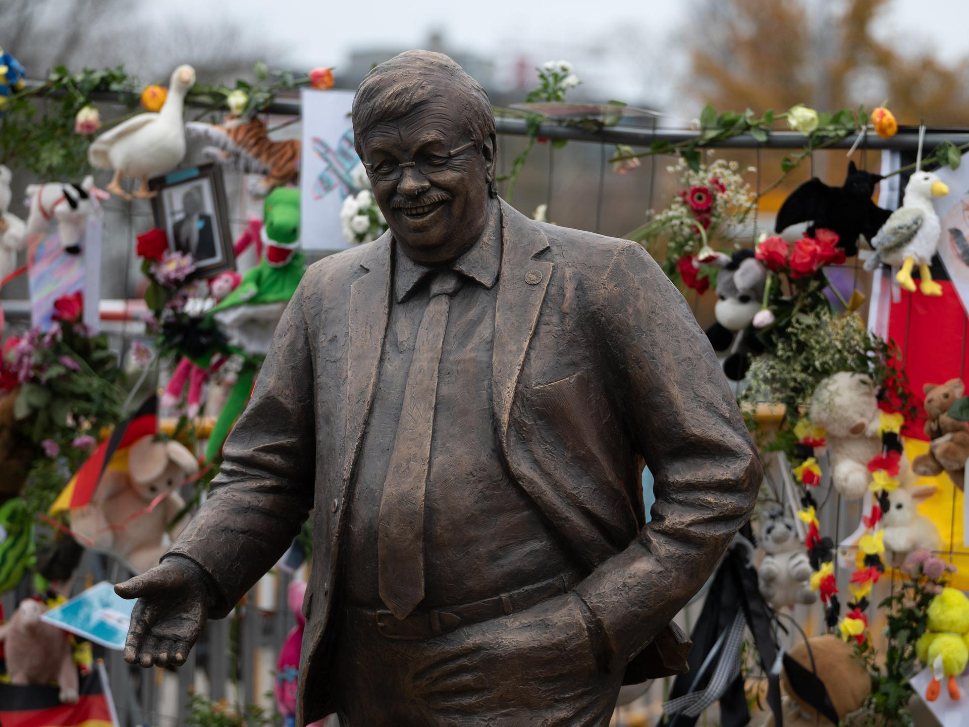 Eine lebensgroße Statue des ermordeten CDU-Politikers Walter Lübcke steht vor der CDU-Parteizentrale in Berlin. Ein Bauzaun dahinter ist mit Blumen und Bildern geschmückt.
