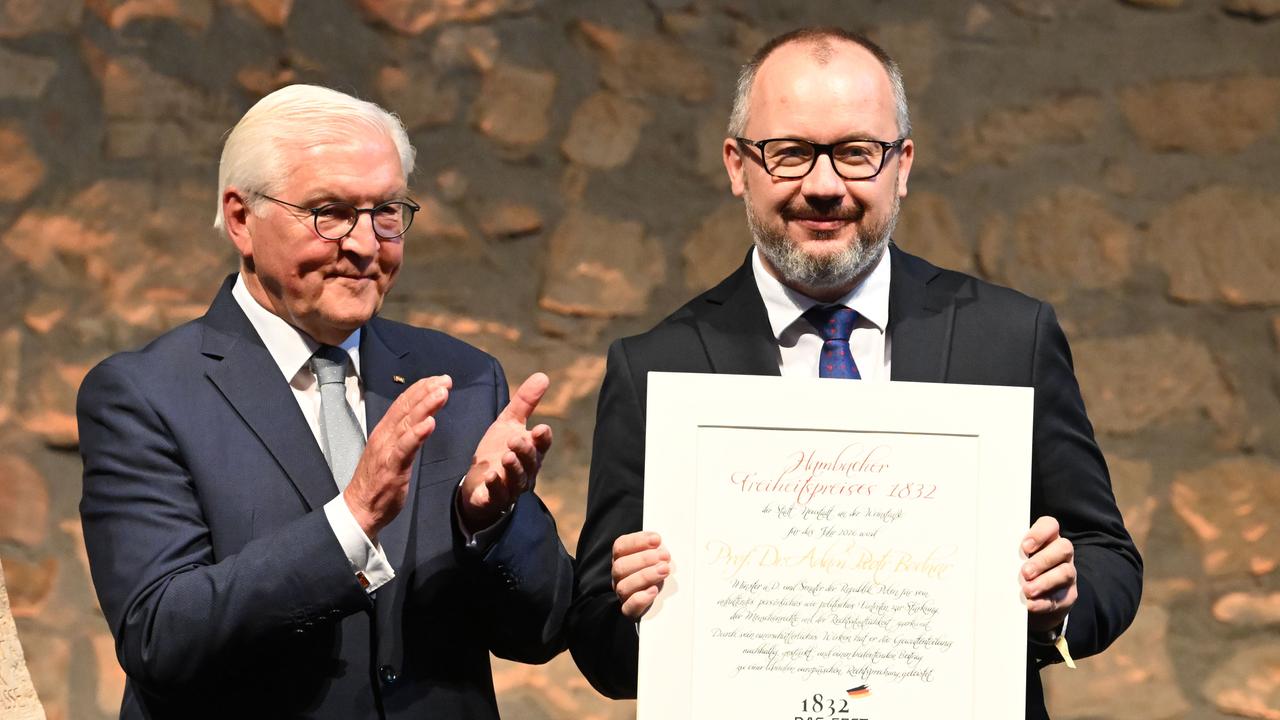 Die beiden stehen nebeneinander vor einer Steinwand. Bodnar hält lächenldn die Preisurkunde vor sich; Steinmeier applaudiert.