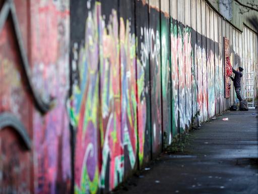 Ein Graffiti-Künstler besprüht im pro-britischen Teil von Belfast eine Friedensmauer