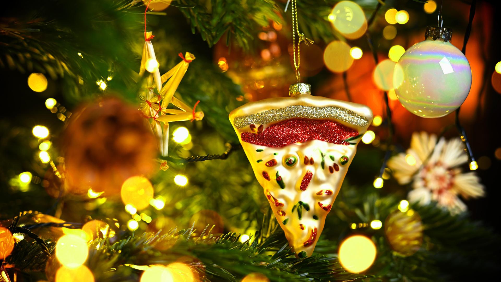 Weihnachtsschmuck in Form eines Pizzastücks hängt an einem Weihnachtsbaum Weihnachtsschmuck in Form eines Pizzastücks hängt an einem Weihnachtsbaum