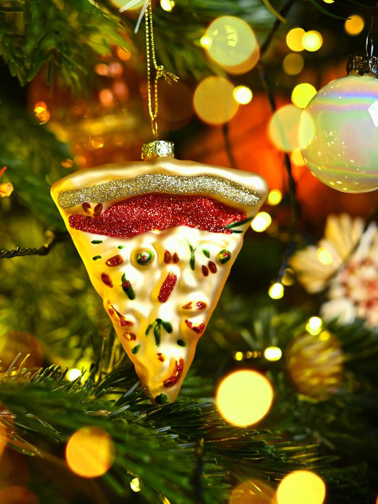 Weihnachtsschmuck in Form eines Pizzastücks hängt an einem Weihnachtsbaum