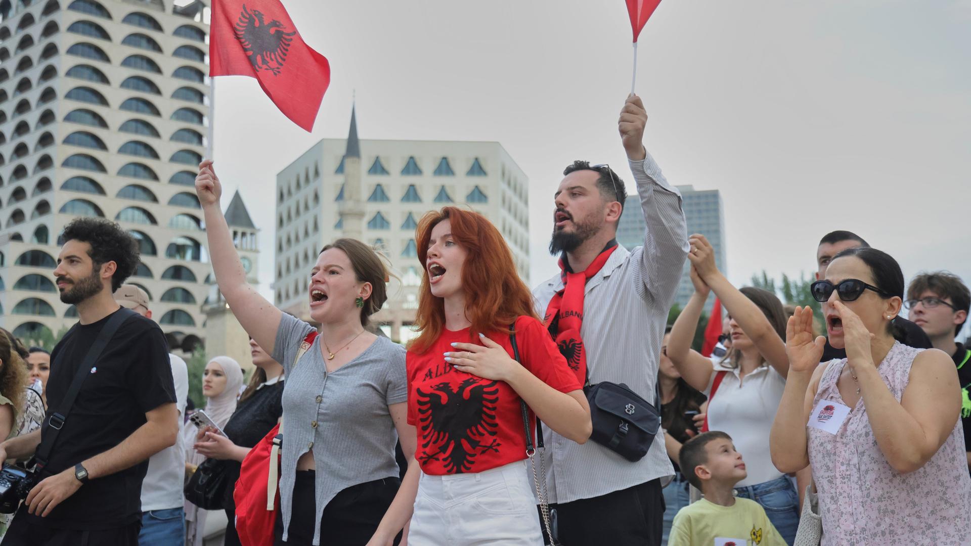 Albanien, Tirana: Demonstranten schwenken albanische Flaggen während einer Demonstration gegen ein luxuriöses Bauprojekt.