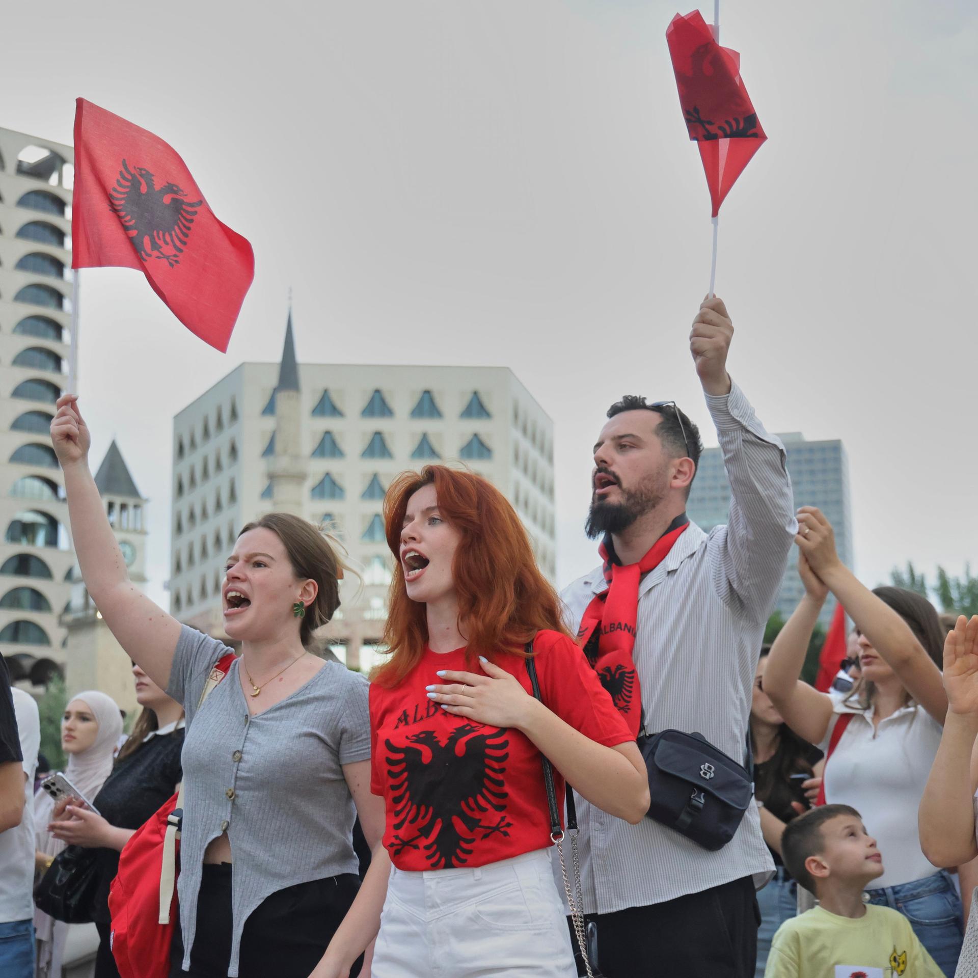 Albanien, Tirana: Demonstranten schwenken albanische Flaggen während einer Demonstration gegen ein luxuriöses Bauprojekt.