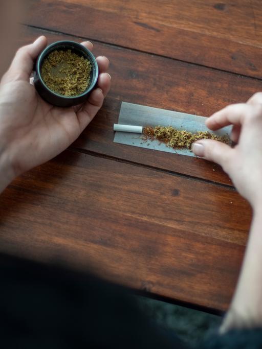 Eine Frau baut mit Marihuana einen Joint (Tüte). Zu sehen sind eine kleine Dose mit Marihuana und auf dem Tisch ein noch nicht gedrehter Joint. Copyright: Julia Imo/ picture alliance/photothek