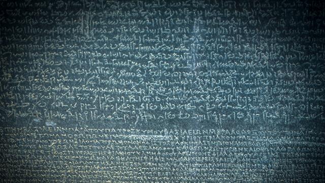 Eine Stein mit Buchstaben. Es ist der Stein von Rosetta aus dem alten Ägypten.