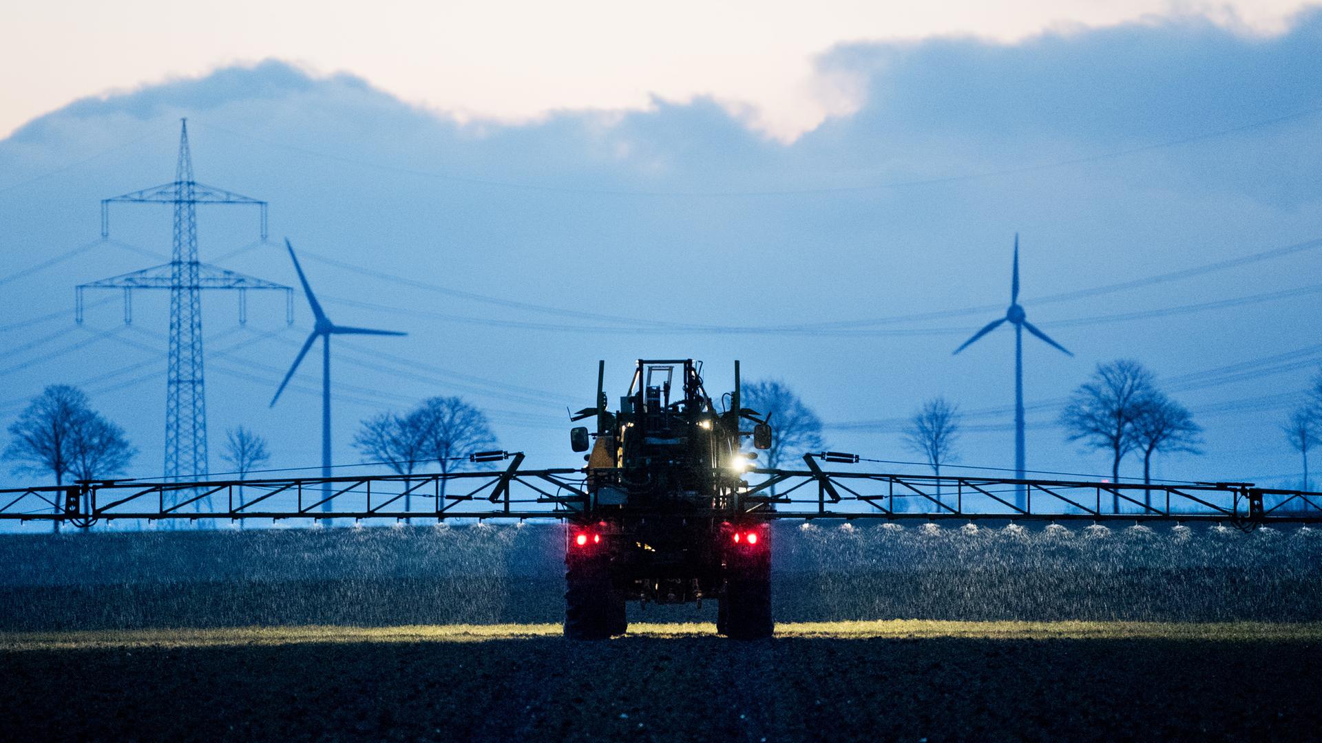 Ein Landwirt düngt mit einem Traktor in der Morgendämmerung ein Feld mit Stickstoffdünger. 