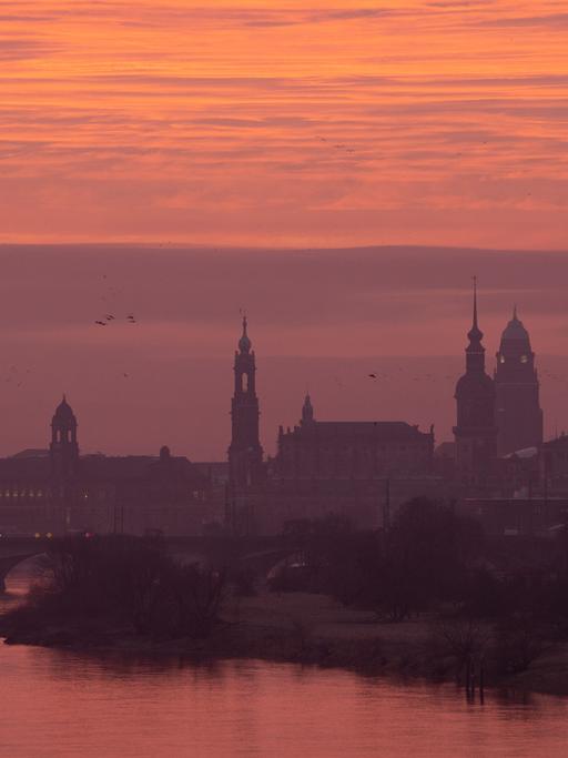 Die Kulisse der Dresdner Altstadt mit der Frauenkirche (l-r), dem Ständehaus, der Katholischen Hofkirche, dem Hausmannsturm, dem Rathausturm und der Kreuzkirche bei Sonnenaufgang.