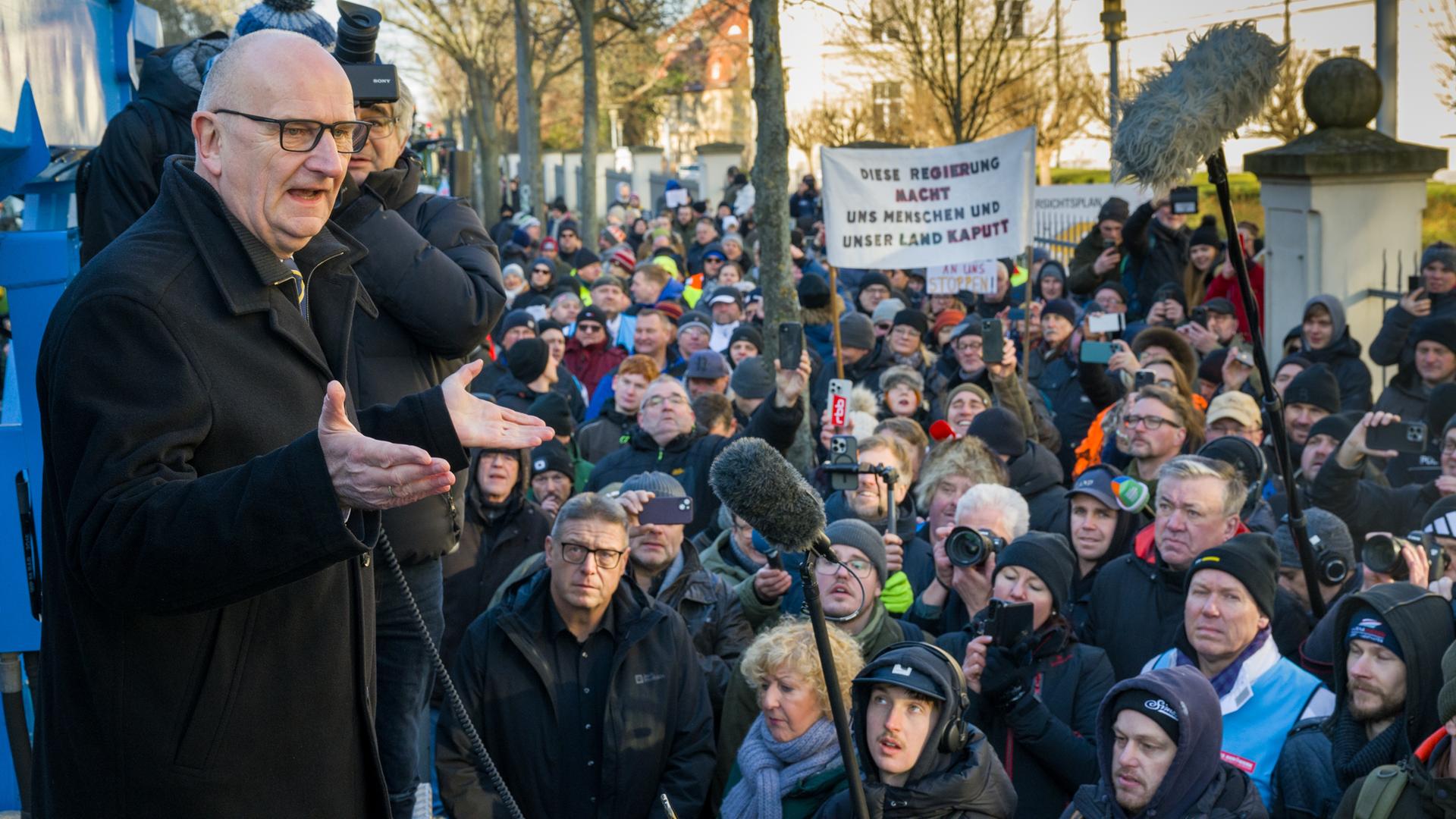 Potsdam: Dietmar Woidke (SPD, l), Ministerpräsident von Brandenburg, spricht vom Hänger eines Lastwagens aus zu Landwirten, die mit ihren Fahrzeugen vor der Staatskanzlei demonstrieren.