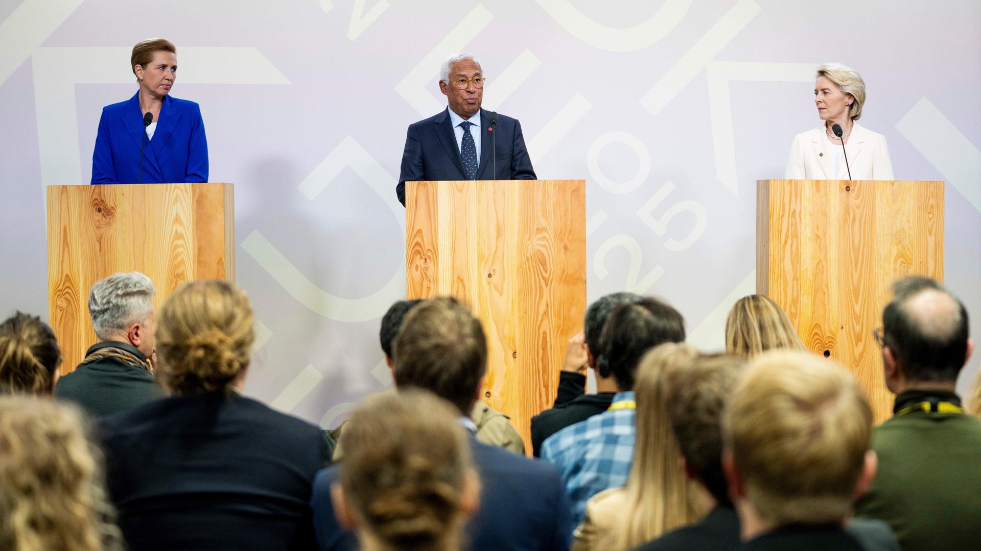 Mette Frederiksen, Antonio Costa und Ursula von der Leyen stehen an drei Redepulten nebeneinander und informieren die Presse. 