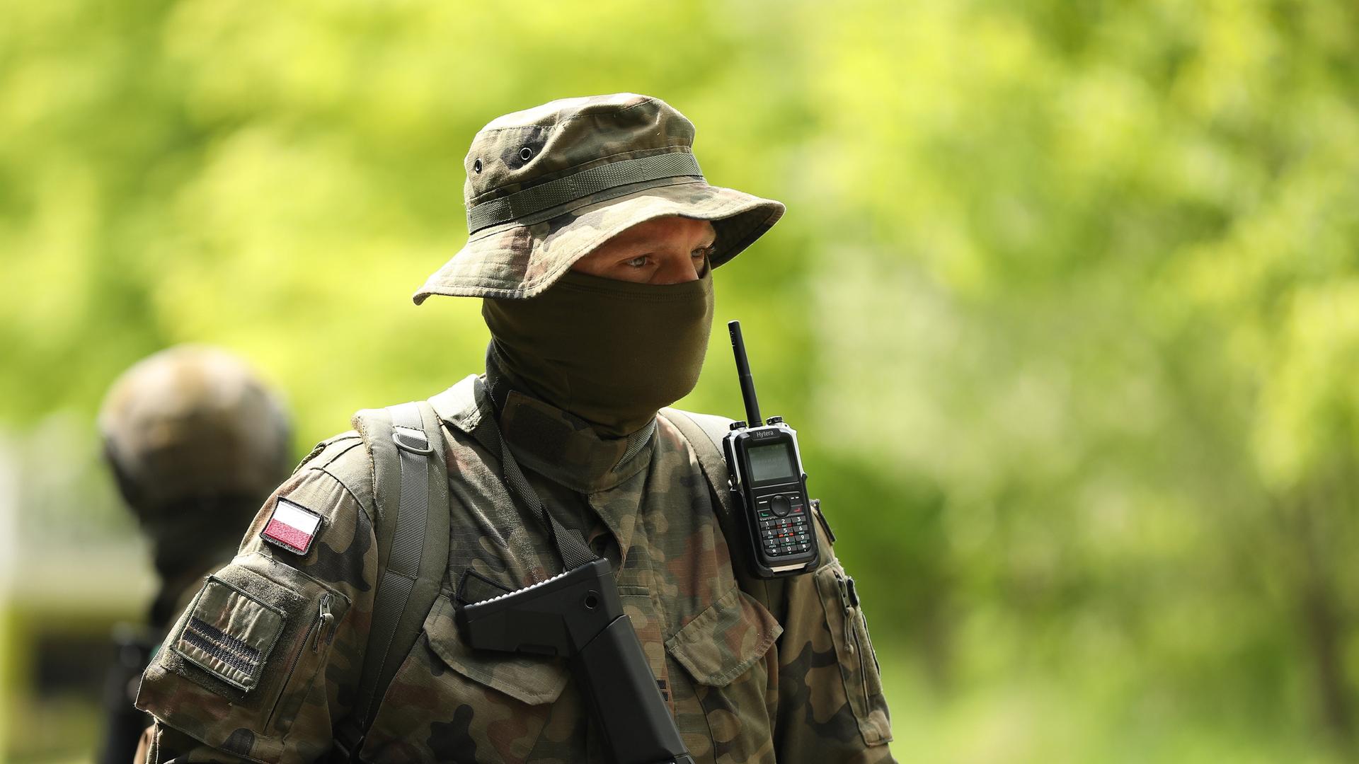 Ein vermummter polinischer Soldat trägt Uniform, Schlapphut und einen schwazren Schal vor seinem Gesicht Ein vermummter polinischer Soldat trägt Uniform, Schlapphut und einen schwazren Schal vor seinem Gesicht