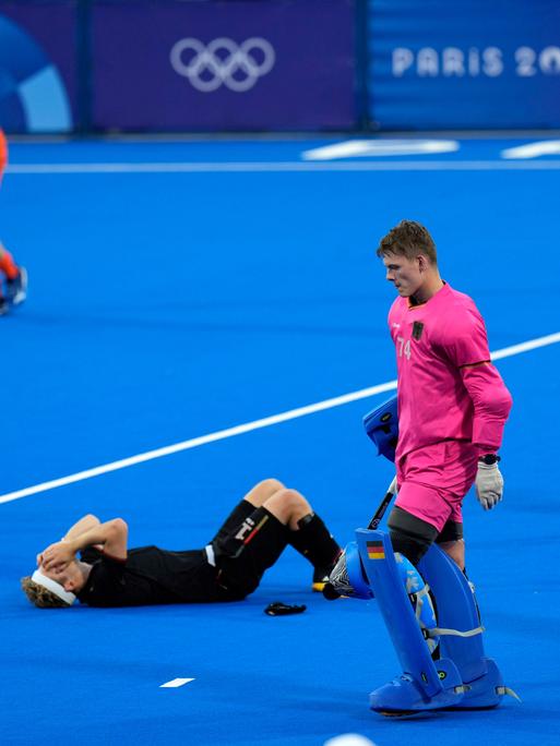 Der deutsche Hockeyspieler Thies Prinz liegt liegt auf dem Boden und hat die Hände vor das Gesicht geschlagen.