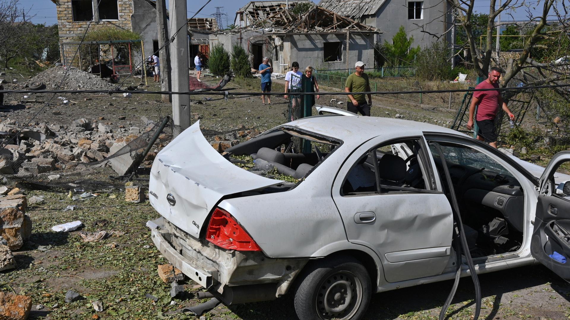 26.08.2024, Ukraine, Ussatowe: Menschen gehen vor ihren beschädigten Häusern nach einem russischen Raketenangriff.