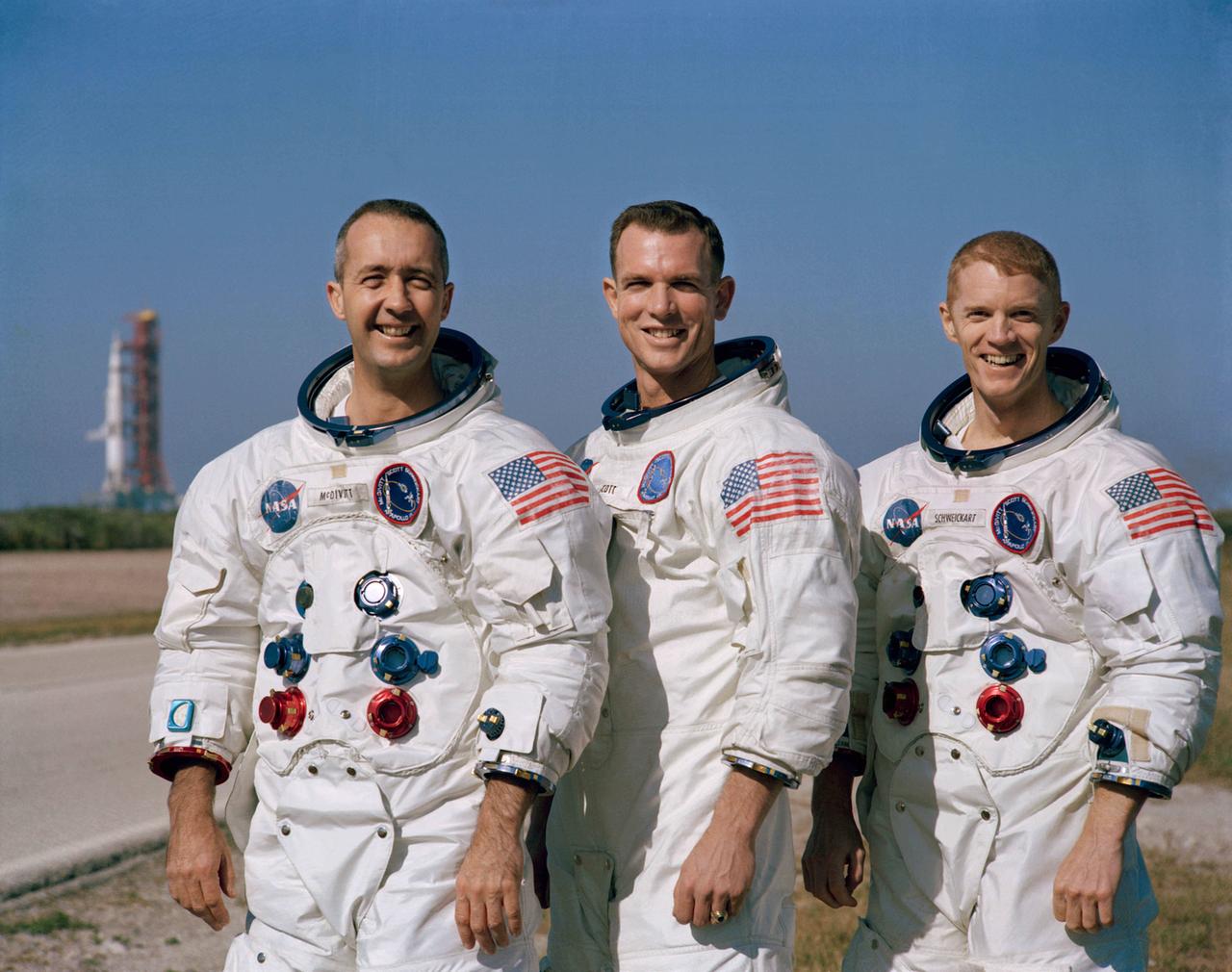 Drei Männer in Raumanzügen stehen vor der Apolla 8-Startrampe in der kargen Landschaft von Merritt Island, Florida.