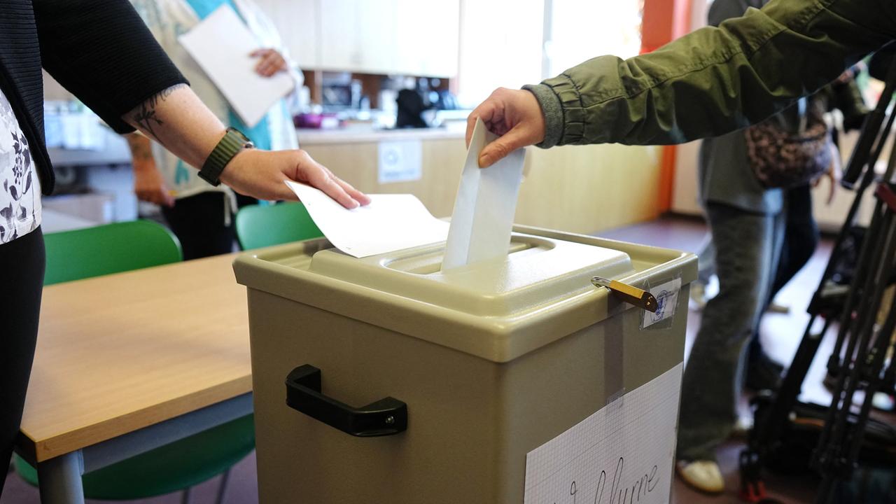 Ein Wähler wirft seinen gefalteten Stimmzettel in die Wahlurne in einem Wahllokal. 