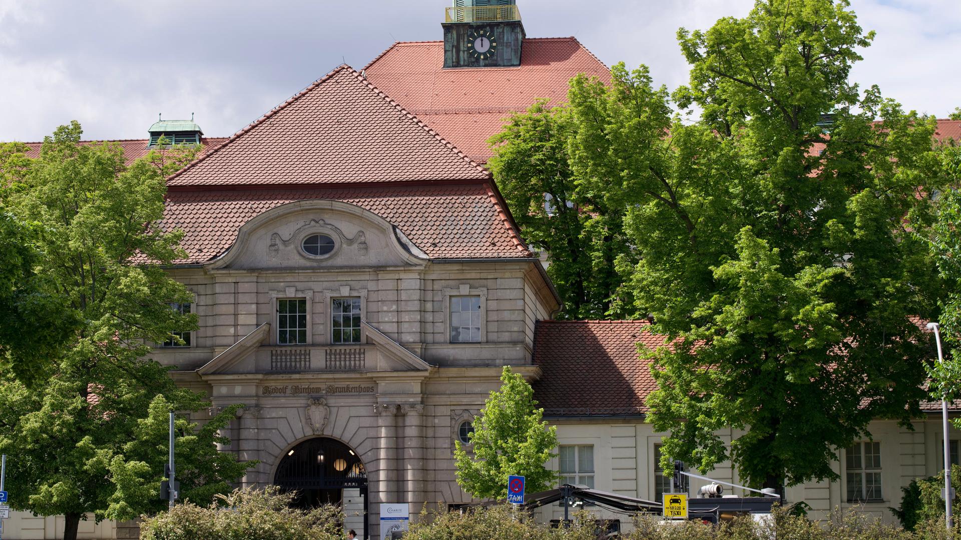 Ein großes Haus aus hellen Steinen steht zwischen Bäumen. Ein großes Haus aus hellen Steinen steht zwischen Bäumen.