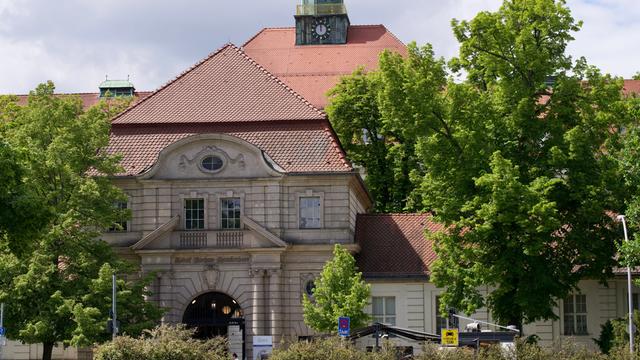Ein großes Haus aus hellen Steinen steht zwischen Bäumen.