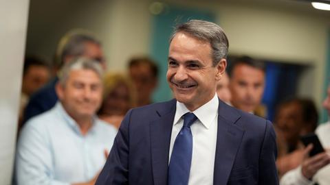 Griechenlands Regierungschef Kyriakos Mitsotakis kommt lächelnd zu einer Veranstaltung. 