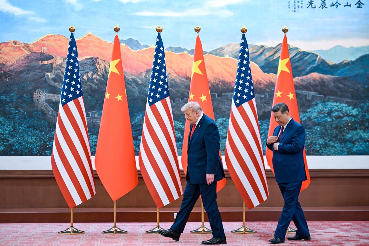 US-Präsident Donald Trump und der chinesische Staatschef Xi Jinping gehen vor chinesischen und US-Flaggen entlang.