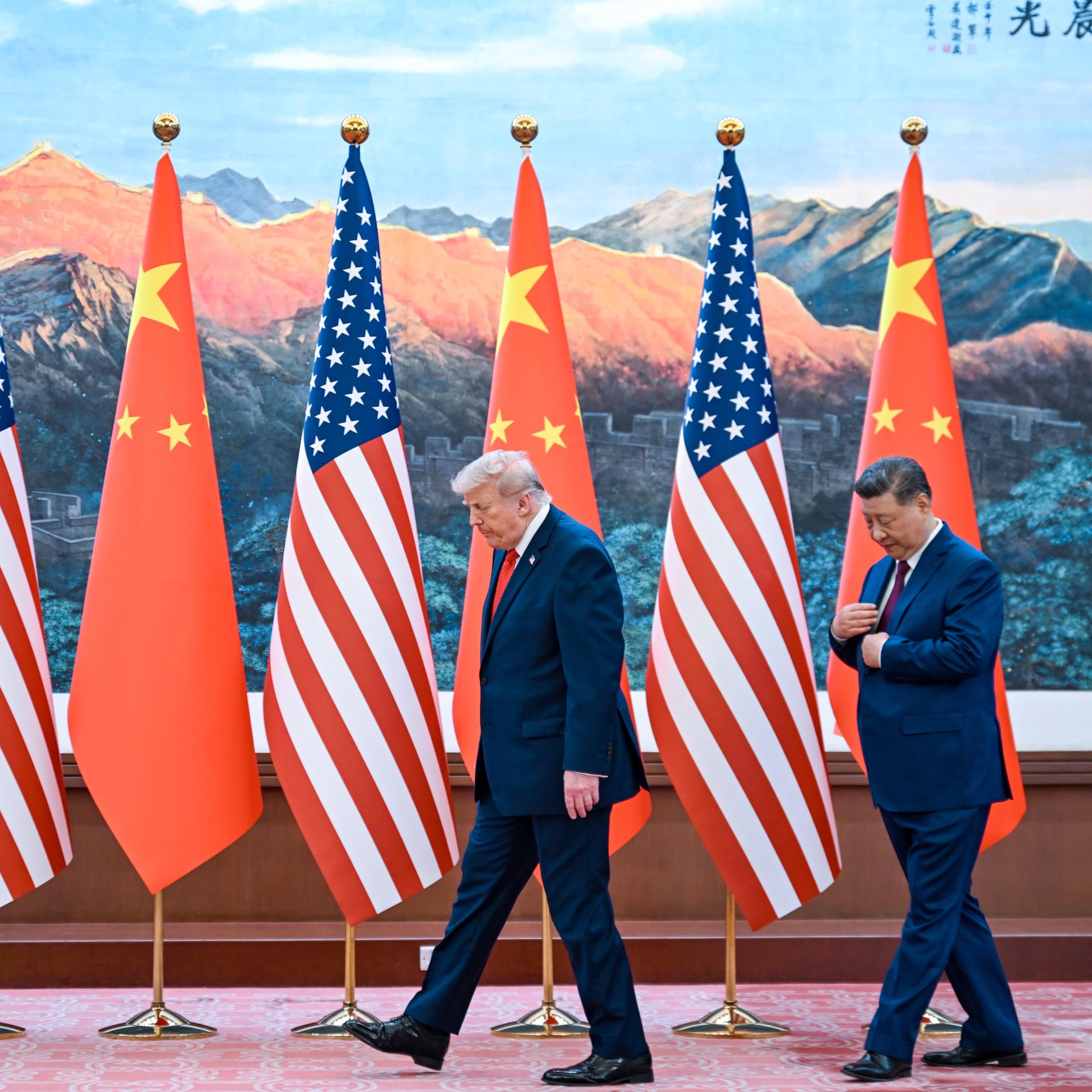 US-Präsident Donald Trump und der chinesische Staatschef Xi Jinping gehen vor chinesischen und US-Flaggen entlang.