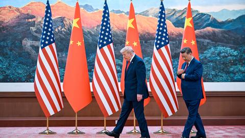 US-Präsident Donald Trump und der chinesische Staatschef Xi Jinping gehen vor chinesischen und US-Flaggen entlang.
