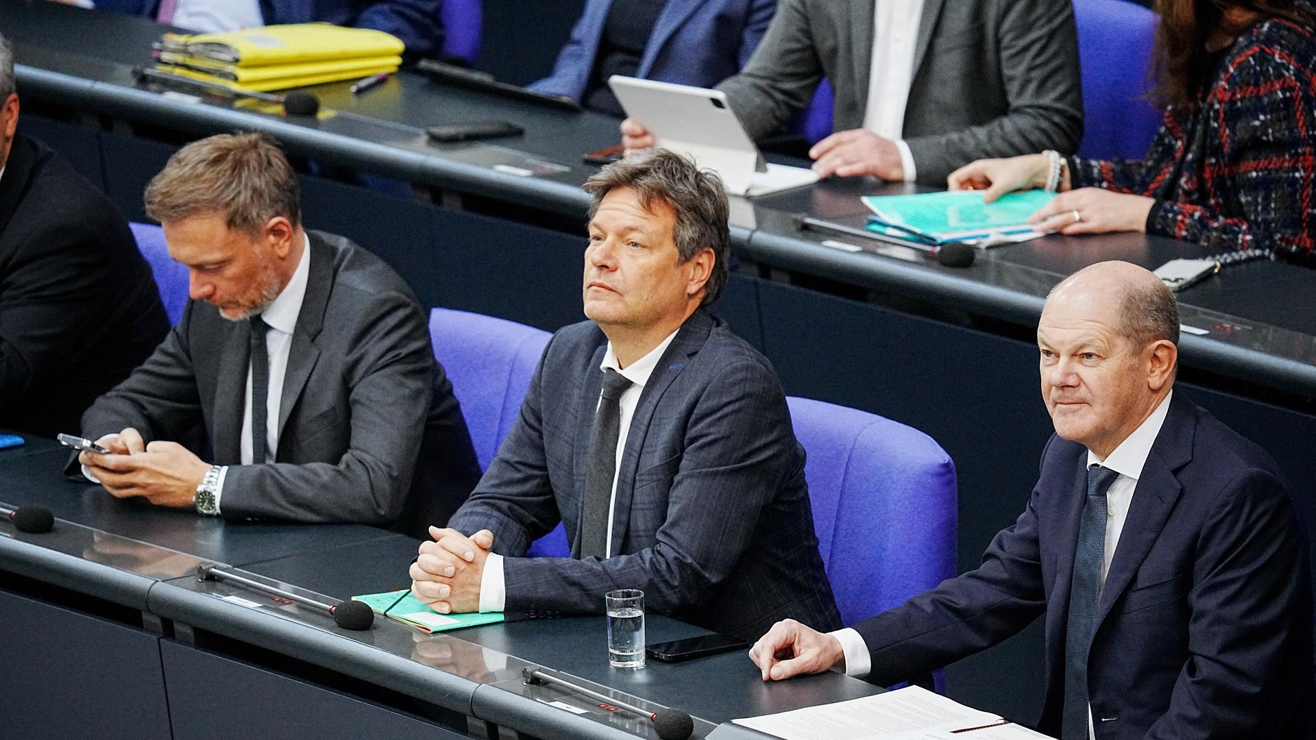 Bundeskanzler Olaf Scholz (SPD, r) sitzt im Bundestag neben Christian Lindner (FDP, l), Bundesminister der Finanzen, und Robert Habeck (Bündnis 90/Die Grünen, M), Bundesminister für Wirtschaft und Klimaschutz