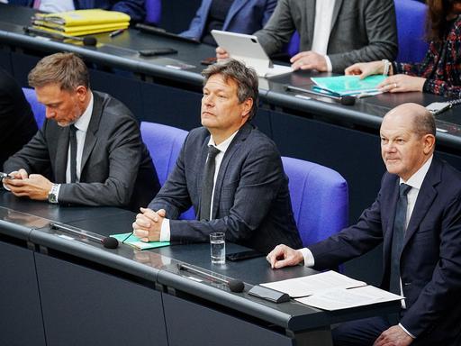 Bundeskanzler Olaf Scholz (SPD, r) sitzt im Bundestag neben Christian Lindner (FDP, l), Bundesminister der Finanzen, und Robert Habeck (Bündnis 90/Die Grünen, M), Bundesminister für Wirtschaft und Klimaschutz