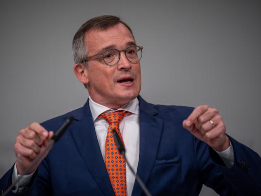 Ein Mann im Anzug mit Brille spricht an einem Rednerpult.