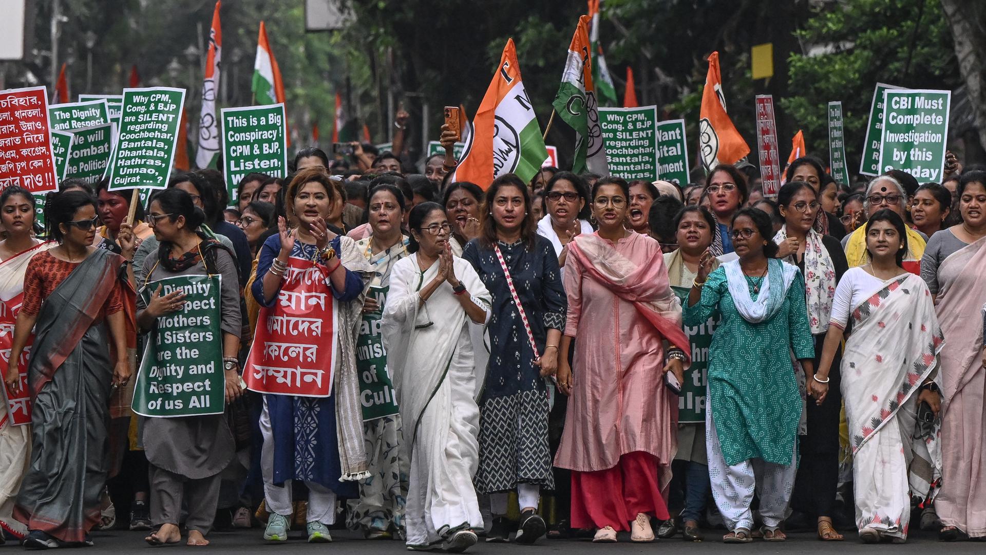 Hunderte Frauen ziehen durch eine Straße der indischen Stadt Kolkata. Sie klatschen und tragen Plakate.