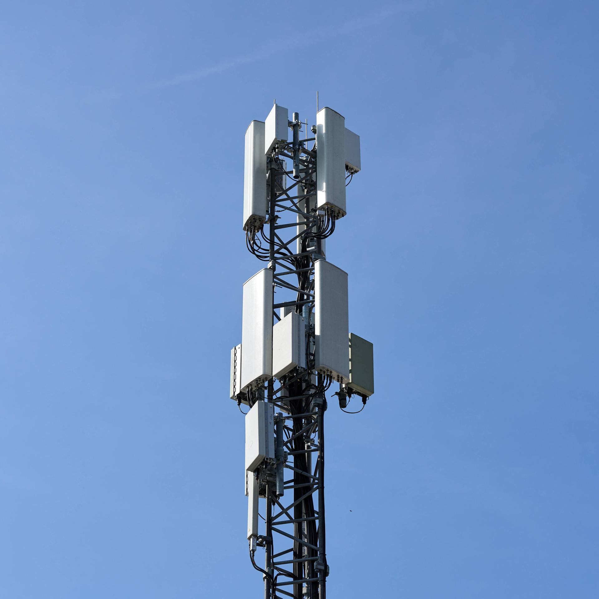 Ein Mobilfunkmast ragt in den blauen Himmel.