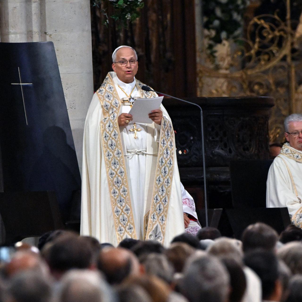 Der Papst während der Andacht in der Kathedrale Notre Dame in Paris - er hält ein Blatt Papier in den Händen und spricht. Am unteren Bildrand sind zahlreiche Besucher von hinten zu sehen.
