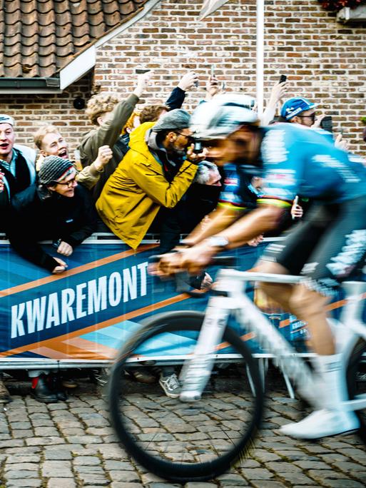 Ein begeistertes Publikum jubelt einem vorbeifahrenden Rennradfahrer zu. Ein begeistertes Publikum jubelt einem vorbeifahrenden Rennradfahrer zu.