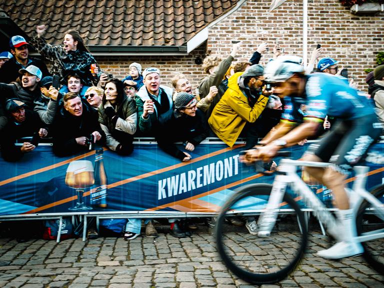 Ein begeistertes Publikum jubelt einem vorbeifahrenden Rennradfahrer zu. Ein begeistertes Publikum jubelt einem vorbeifahrenden Rennradfahrer zu.